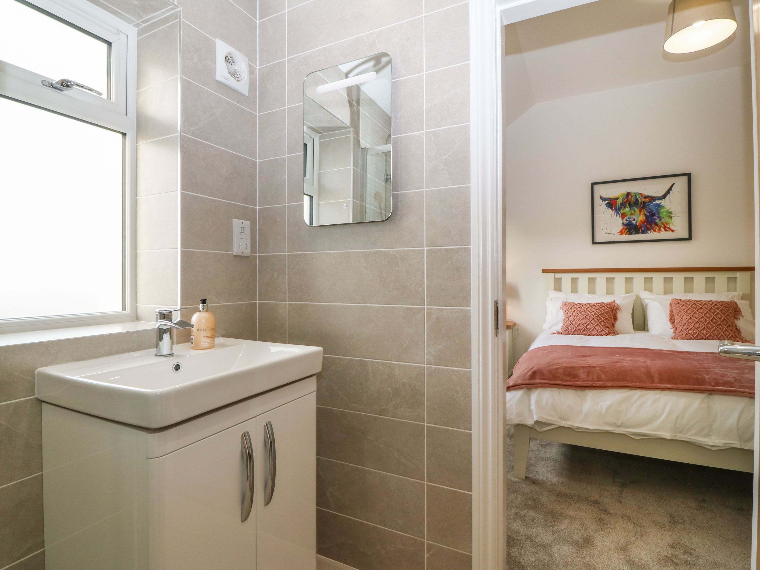 A bathroom with a sink, mirror, and window.