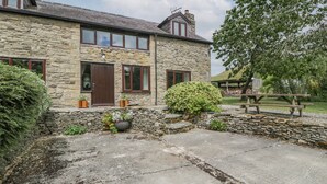 A stone house with a stone facade, a wooden door, and a small garden with a bench. - Bullfinch Cottage (Leominster)