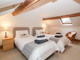 Un dormitorio acogedor con dos camas, un tragaluz y una silla de mimbre.