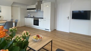 Eine moderne Küche mit weißen Schränken, einem eingebauten Backofen und einem Essbereich mit Tisch und Stühlen.