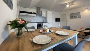 Eine moderne Küche mit weißen Schränken, einem Holztisch gedeckt mit Tellern, Gläsern und Besteck.
