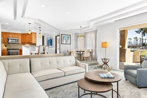 Relax in a spacious room with a living area, dining space, and kitchenette, offering a view of palm trees.