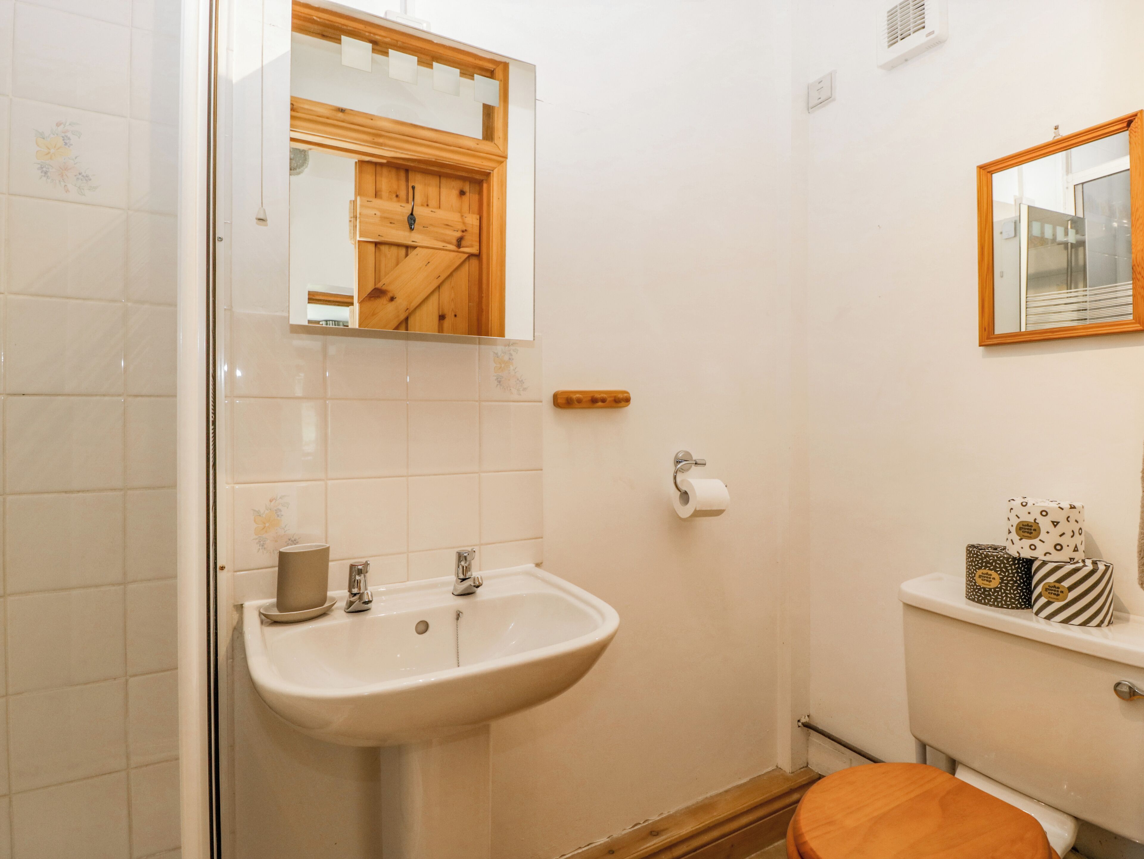 A bathroom with a sink, toilet, and a wooden-framed mirror.