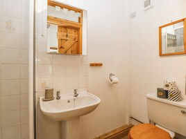 Un baño con lavamanos, inodoro y espejo con marco de madera.