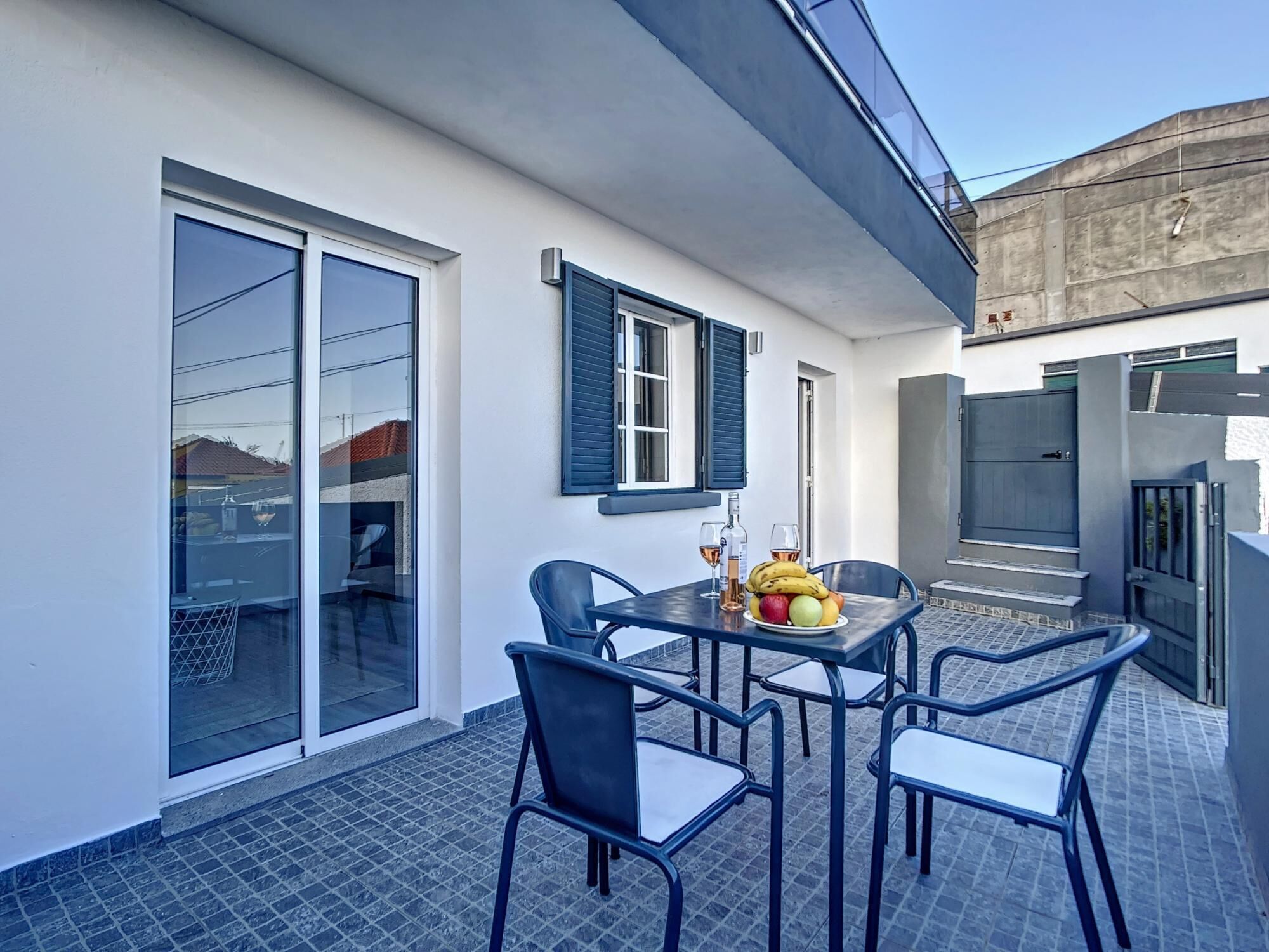 A patio with a table and chairs, a fruit bowl, and a bottle of wine.