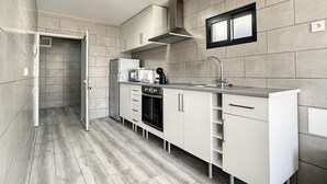 Ett modernt kök med vita skåp, en diskho i rostfritt stål och en inbyggd ugn.