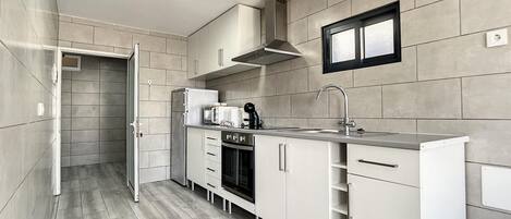 A modern kitchen with white cabinets, a stainless steel sink, and a built-in oven.