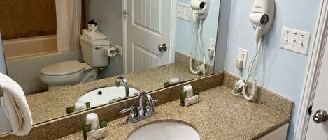 A bathroom with a sink, mirror, towel rack, and hairdryer.