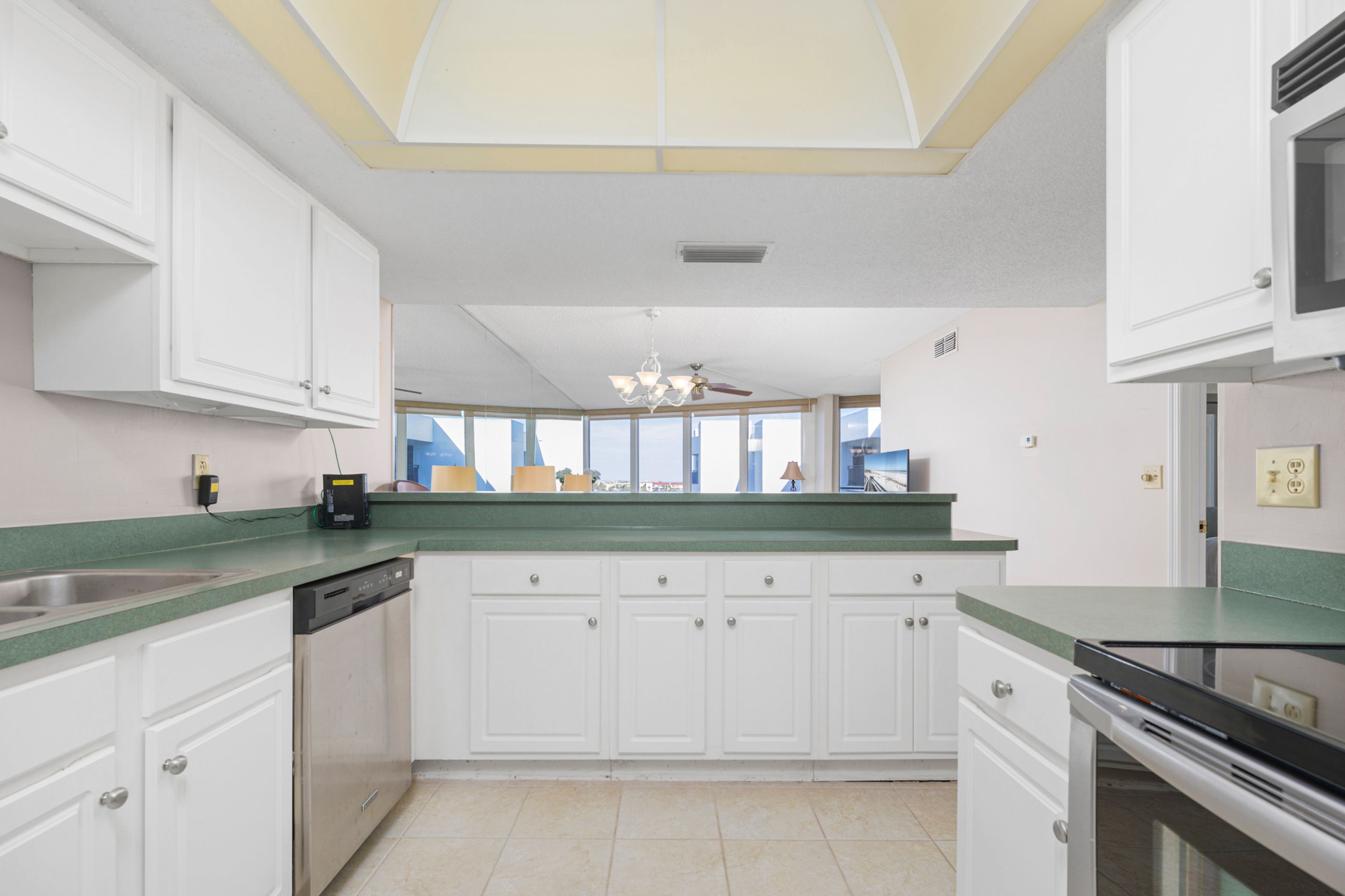 A kitchen with white cabinets, a green countertop, a dishwasher, and a microwave.
