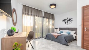 A modern bedroom with a bed, a desk, a chair, and a large window with curtains. - Villa Borealis (Rasa)