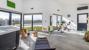 A modern spa room with a massage table, a hot tub, and exercise equipment. - Villa Borealis (Rasa)