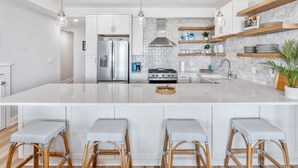 A modern kitchen with a large island, white cabinetry, and built-in shelves. - BRAND NEW OCEANFRONT 3 Bedroom 2 bath 1st floor villa (Honu) (Cape May)