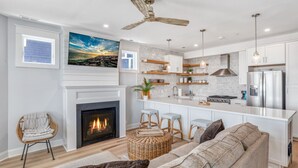 A modern kitchen with a fireplace, white cabinetry, and a large island.