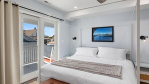 A bedroom with a large bed, a view of the outside, and a window with curtains.