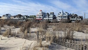 A beachfront property with multiple houses, a wooden fence, and sandy dunes.