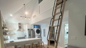 Eine moderne Küche mit einer zentralen Kochinsel, einer Treppe und einem Wohnbereich mit einer Couch.