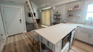 Eine moderne Küche mit einer zentralen Kochinsel, integrierten Geräten und einem Essbereich mit grauem Sofa.