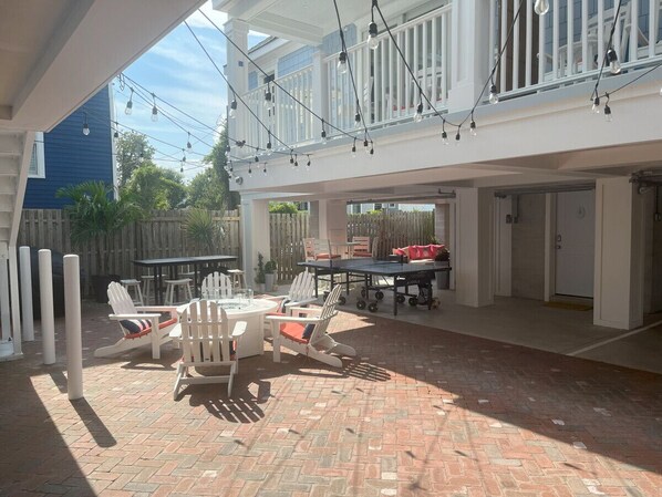 An outdoor patio area with a brick floor, white furniture, and string lights.