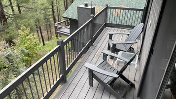 Une terrasse en bois avec une rambarde, une petite chaise longue et un banc.