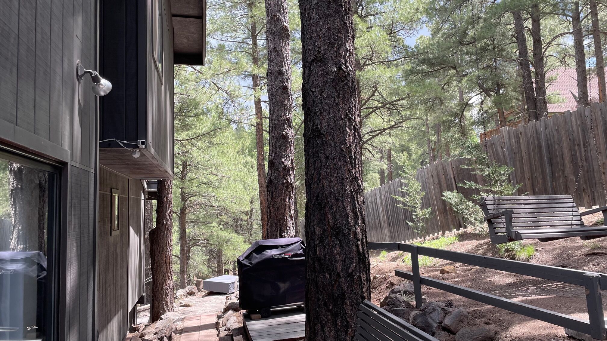 Une cabane avec une terrasse, un barbecue et un banc.