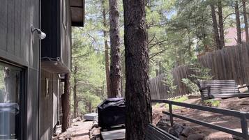 Une cabane avec une terrasse, un barbecue et un banc.