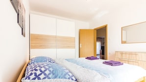 Un dormitorio con una cama, un armario, un espejo y una puerta que da a otra habitación.