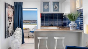Une cuisine moderne avec vue, dotée d’un mur recouvert de carreaux bleus, d’un plan de travail en bois et d’un coin bar avec des tabourets.
