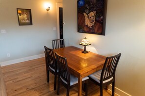 Een eethoek met een houten tafel en stoelen, een wandlamp en een lijst met een foto van een hond.