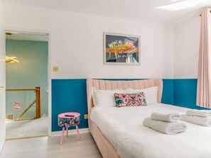 A bedroom with a bed, a small round table, a wall-mounted picture, and a door leading to another room. - Dawns House in the Peaks overlooking the mill pond (Cromford)