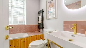 A bathroom with a white toilet, a sink with a gold faucet, and a wooden vanity. - Dawns House in the Peaks overlooking the mill pond (Cromford)