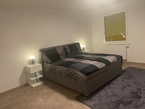 Une chambre à coucher avec un lit, des tables de chevet, une fenêtre et un tapis.