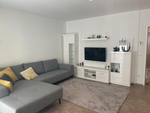A modern living room with a grey sectional sofa, a flat-screen TV, a white entertainment unit, and a glass cabinet. - ★ Perfect Accommodation for Families in Vienna, Austria near Danube Canal ★ (Wien)