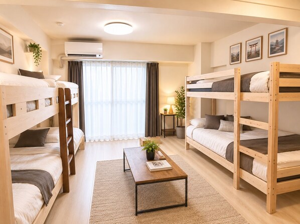 A room with bunk beds, a small table with a plant, a lamp, and a window with curtains.