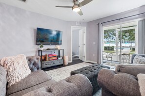 A living room with grey sofas, a flat-screen TV, and a sliding glass door leading to an outdoor area. - Kissimmee 3BR | Heated Pool & Spa | Near Disney (Kissimmee)
