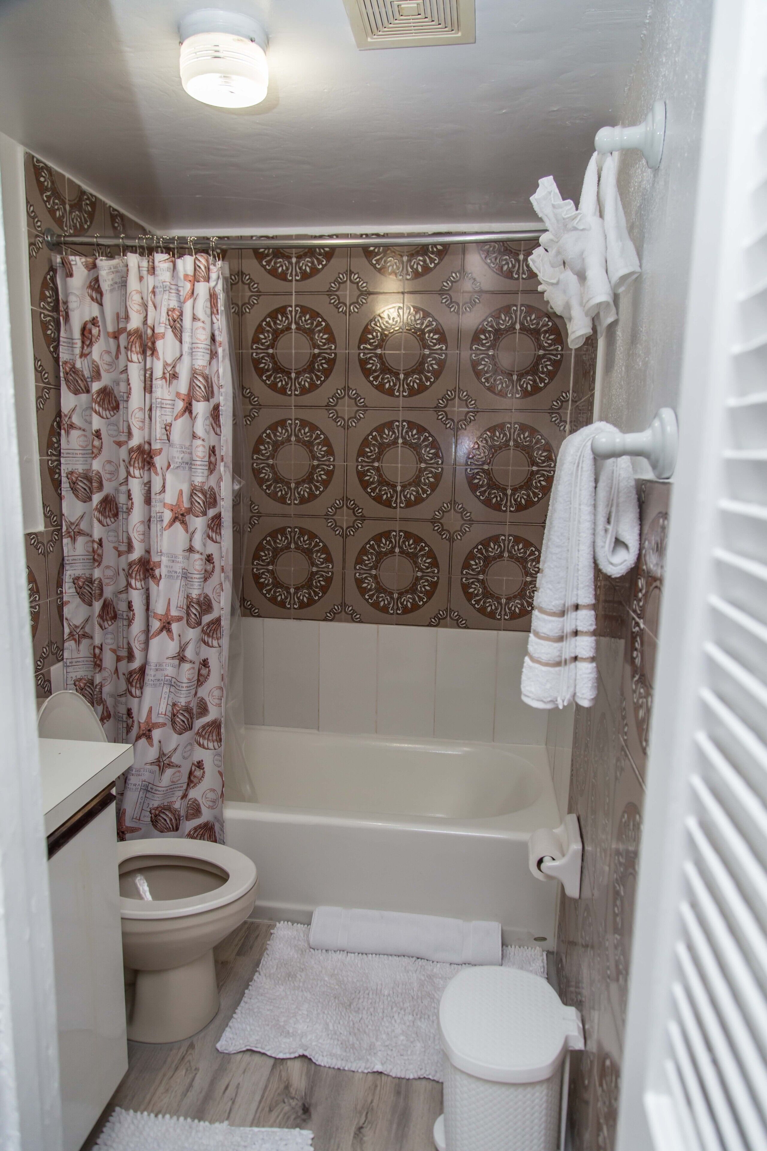Een badkamer met bad, toilet en douchegordijn.