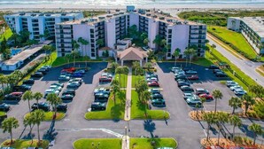 Un hotel con patio central, estacionamiento y vista a la playa.