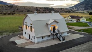 A white building with a sloped roof, a staircase leading to the entrance, and a paved driveway. - The spacious “LavaBarn” in Lava Hot Springs (Lava Hot Springs)