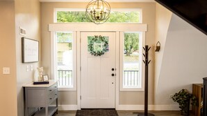 A front entryway with a white door, a small desk with drawers, a coat rack, and a potted plant. - The spacious “LavaBarn” in Lava Hot Springs (Lava Hot Springs)