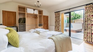 Une chambre avec un grand lit, une armoire en bois et une porte-fenêtre coulissante donnant sur un balcon.