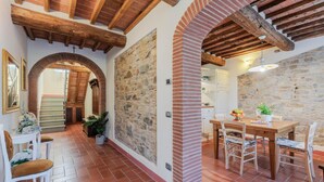 A rustic interior with exposed wooden beams, stone walls, and a tiled floor. - Villa Dondolino in Lucca (Lucca)
