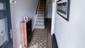 A hallway with a patterned floor, a staircase, a welcome home sign, and a chandelier. - Beautiful House in picturesque Morfa Nefyn. Sleeps 12 and 2 mins from the beach (Morfa Nefyn)