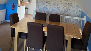 Ein Essbereich mit Holztisch und Stühlen, einer Deckenleuchte und einer Wand mit Muster.