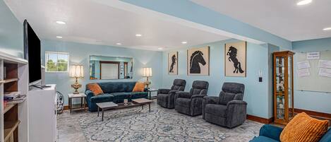 Ein Wohnzimmer mit einem blauen Sofa, einem blauen Sessel, einem gemusterten Teppich und einem Fernseher auf einem Schrank.