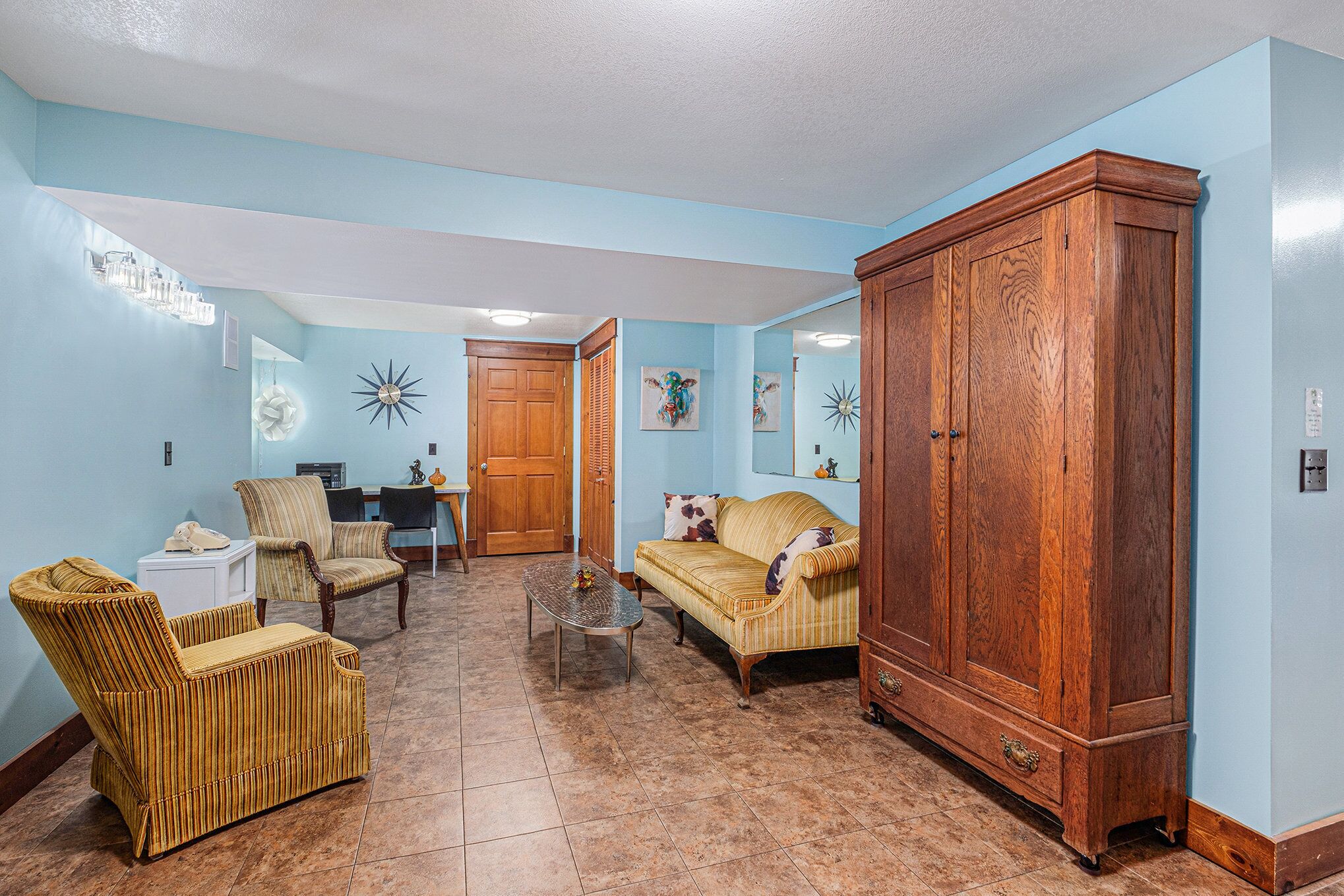 Una sala de estar con un sofá, sillones, un aparador de madera y una zona de comedor al fondo.