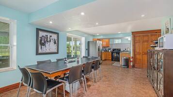 A spacious kitchen with a dining area, featuring a large table, chairs, and a refrigerator.