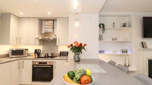 A modern kitchen with a central island, stainless steel appliances, and a hanging light fixture.