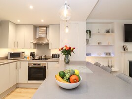 A modern kitchen with a central island, stainless steel appliances, and a hanging light fixture.