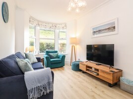 A modern living room with a sofa, teal armchair, and a TV on a wooden stand.