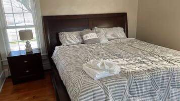 Una cama bien hecha con ropa de cama a rayas y una almohada con la palabra 'Relax'.