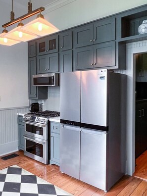 Een koelkast met diepvriezer, een microgolfoven, een oven, een kookplaat